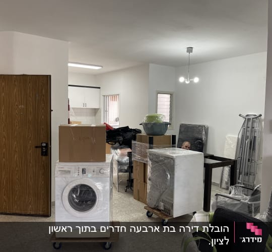 מכונת כביסה על גלגלים, קרטונים וציוד ארוז למעבר דירה